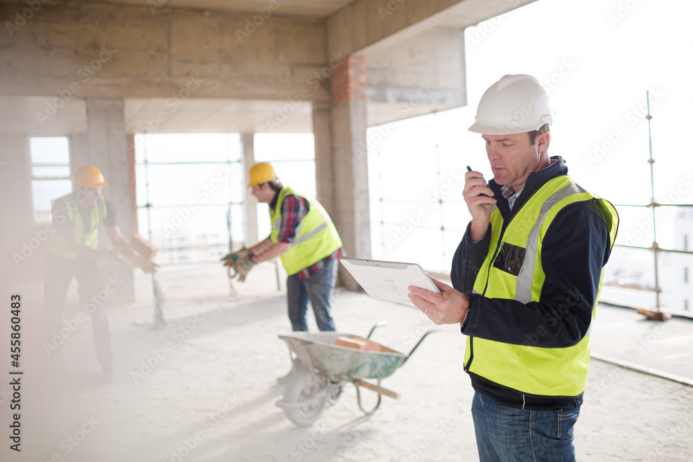 Foreman with digital tablet using walkie-talkie at construction site Foreman with digital tablet using walkie-talkie at construction site