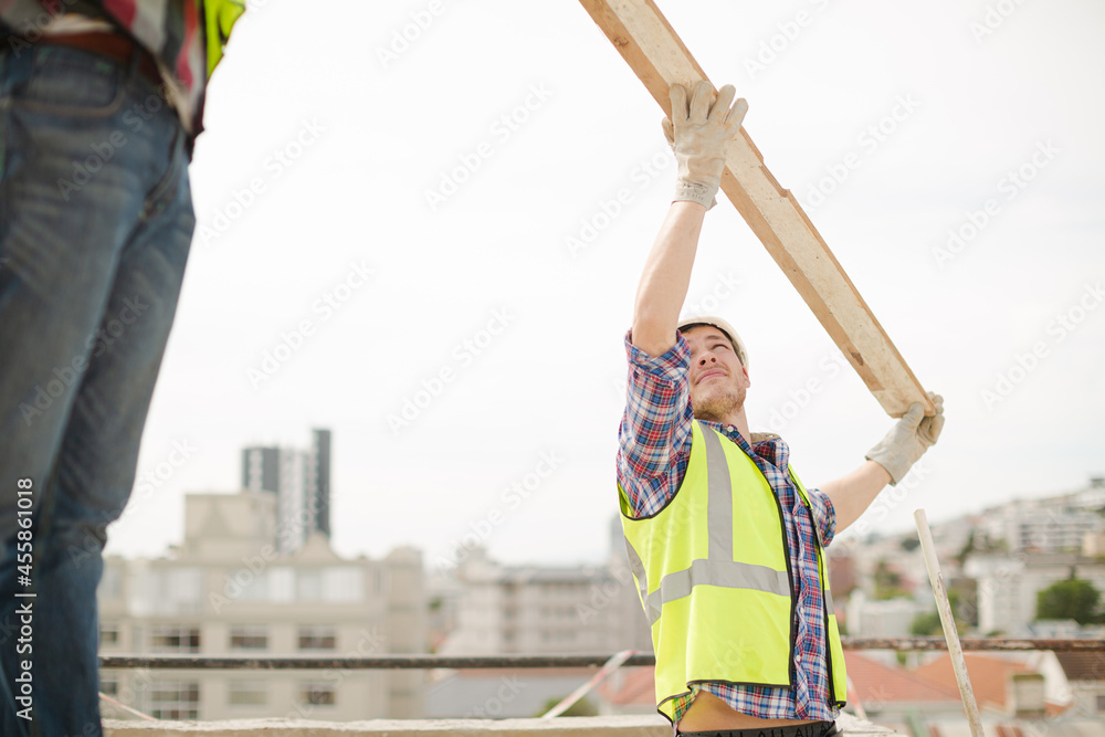Construction workers lifting part at highrise construction site