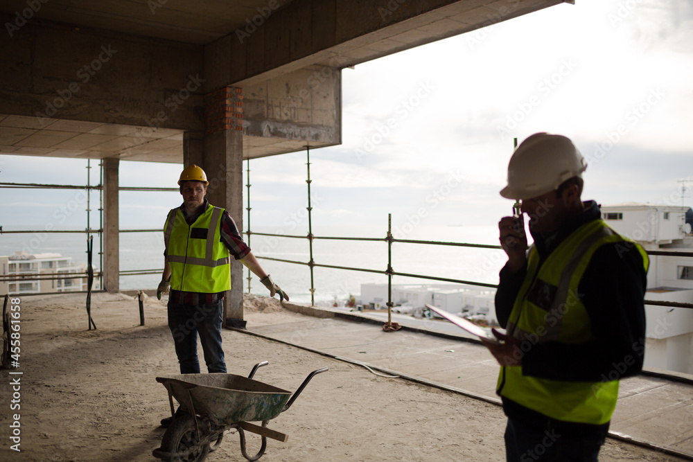 Foreman with digital tablet using walkie-talkie at construction site