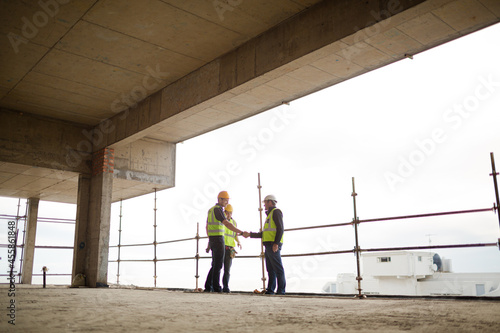 Wallpaper Mural Construction workers handshaking at highrise construction site Torontodigital.ca