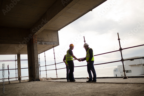 Construction workers handshaking at highrise construction site