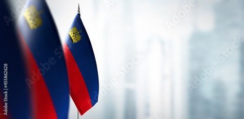 Small flags of Liechtenstein on a blurry background of the city