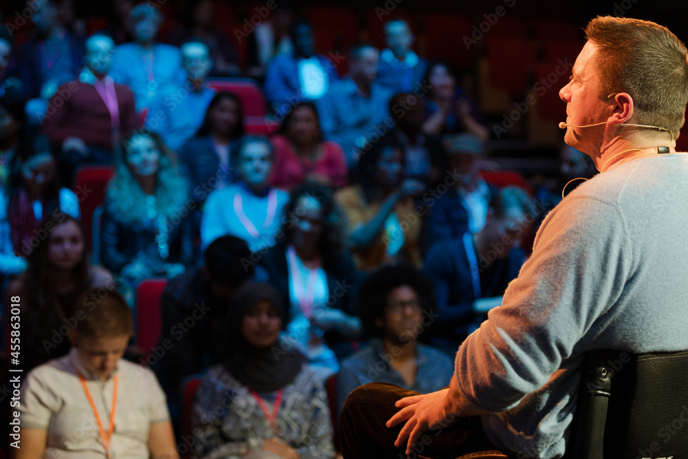 Audience watching male speaker in wheelchair talking on stage Audience watching male speaker in wheelchair talking on stage