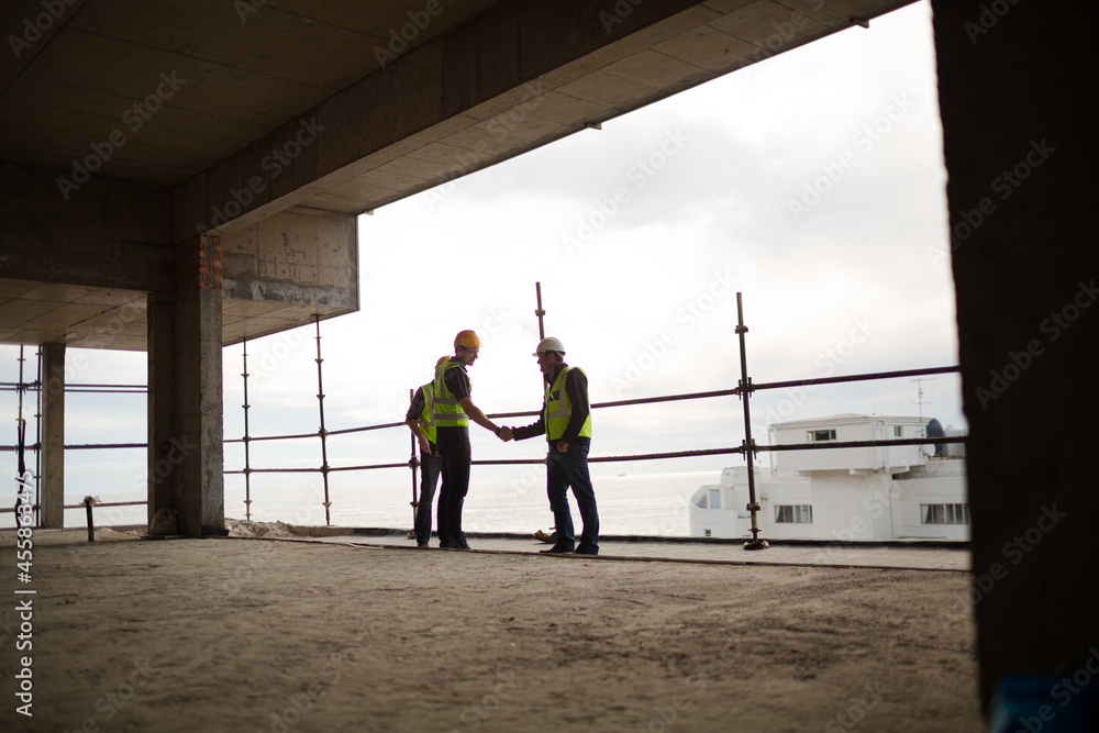 Construction workers handshaking at highrise construction site Construction workers handshaking at highrise construction site
