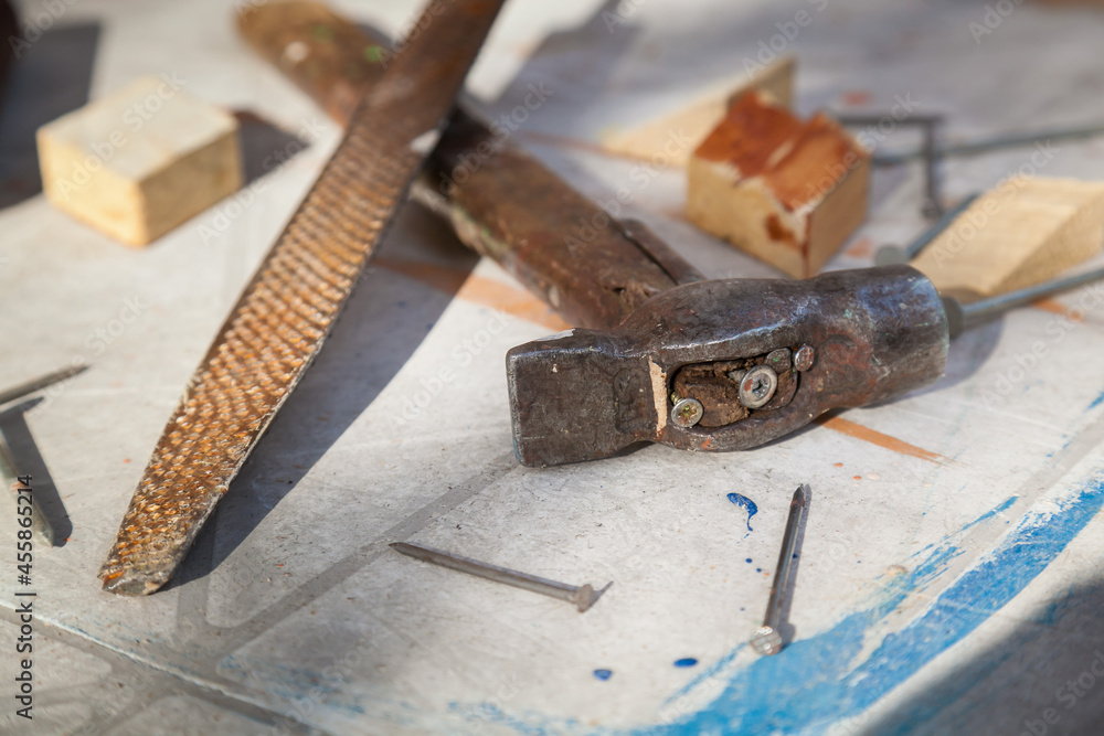 A hammer, a file, sandpaper and nails are on the table. Close-up. A hammer, a file, sandpaper and nails are on the table. Close-up.