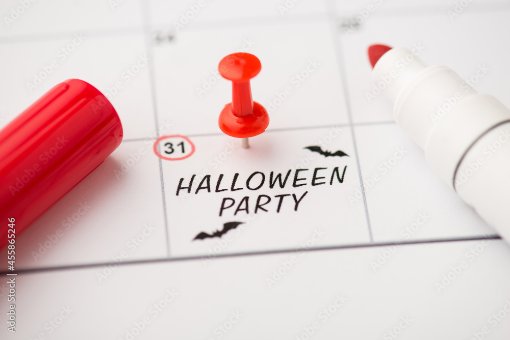 Overhead photo of label date 31 october with inscription halloween party two bats red pin and marker isolated on the calendar background Overhead photo of label date 31 october with inscription halloween party two bats red pin and marker isolated on the calendar background