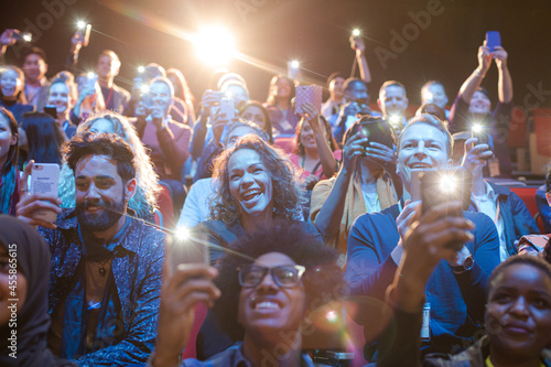 Eager audience with smart phone flashlights in dark auditorium