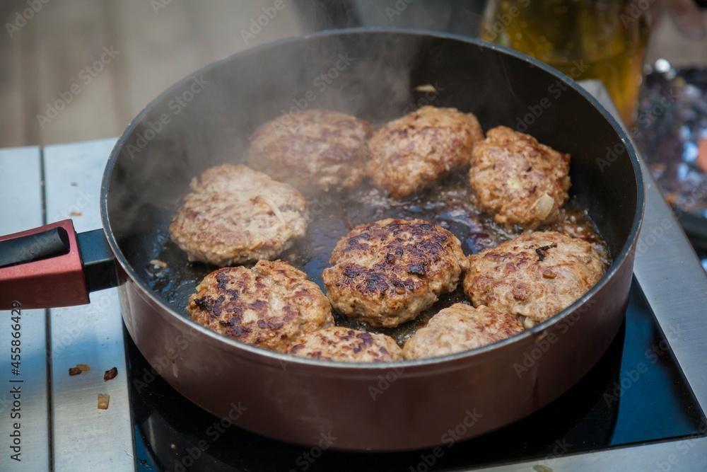 Burger patties are fried in a frying pan. Burger patties are fried in a frying pan.