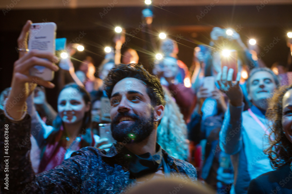 Eager audience with smart phone flashlights in dark auditorium Eager audience with smart phone flashlights in dark auditorium