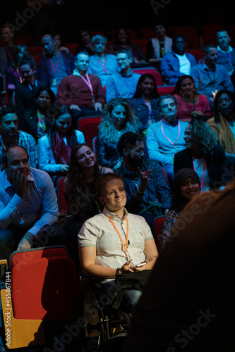 Audience watching male speaker in wheelchair talking on stage