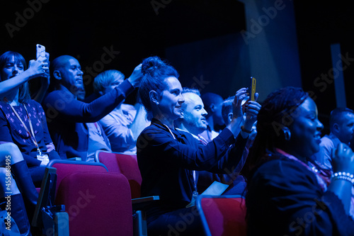 Audience members with smart phones videoing speaker on stage at conference © KOTO