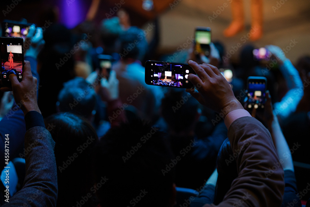 Audience members with smart phones videoing speaker on stage at conference Audience members with smart phones videoing speaker on stage at conference