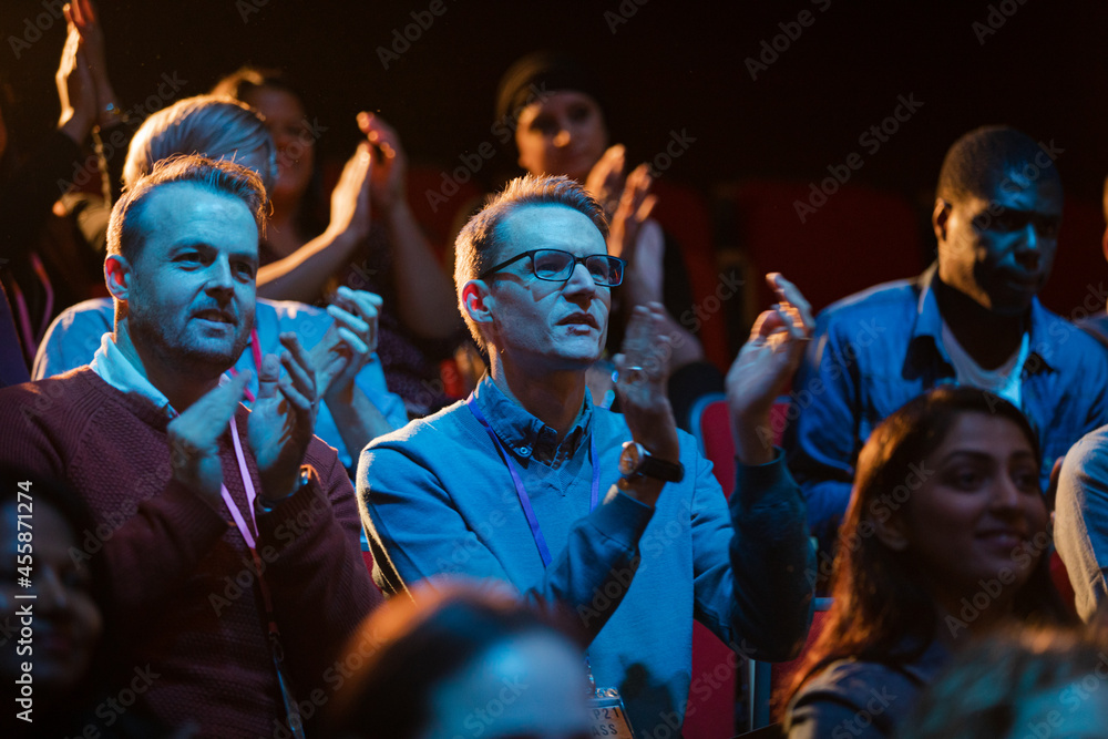 Excited audience clapping in dark room