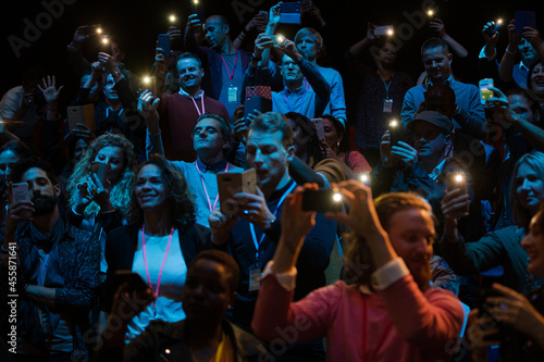 Smiling audience using smart phone flashlights for speaker