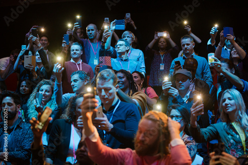 Smiling audience using smart phone flashlights for speaker