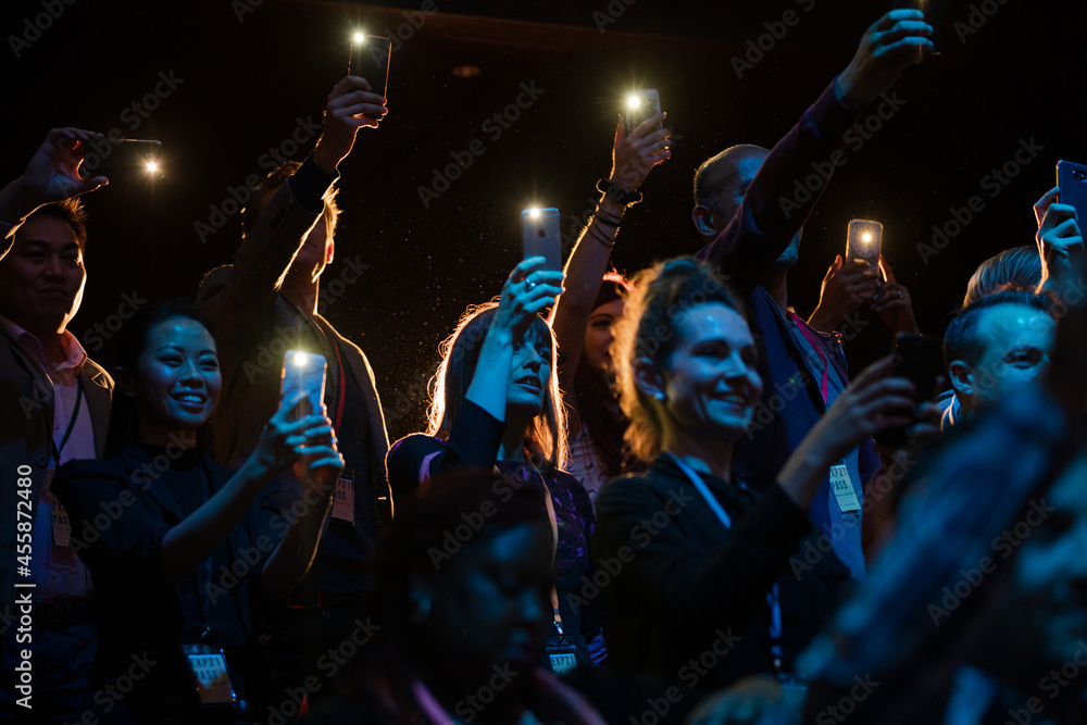 Fototapeta premium Excited audience with smart phone flashlights cheering