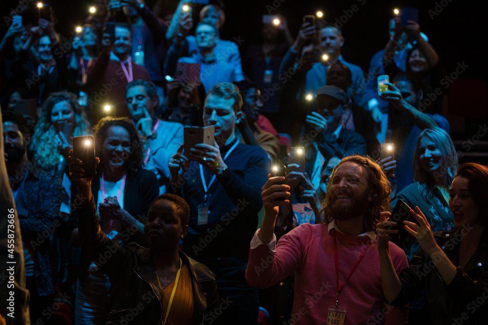 Smiling audience using smart phone flashlights for speaker