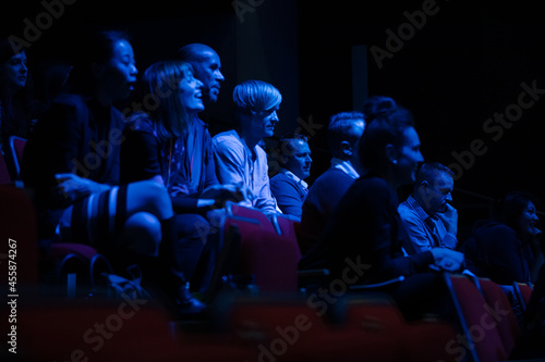 Smiling, enthusiastic audience in dark auditorium