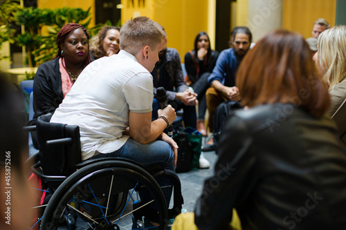 Audience watching speaker in wheelchair talking on stage