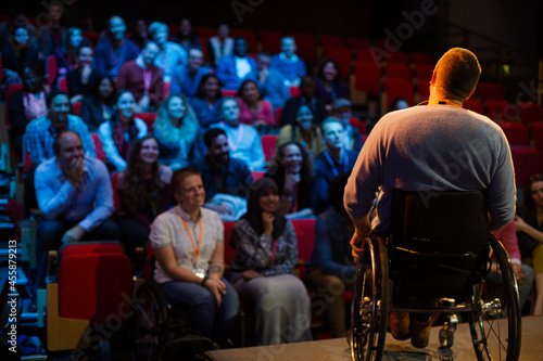 Speaker in wheelchair on stage talking to conference audience