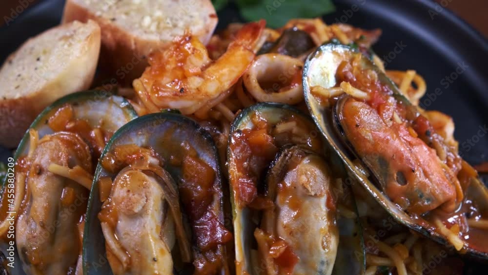 Spaghetti with Freshly Cooked Muscles and Garlic Bread Spinning on a Black Plate Close Up Spaghetti with Freshly Cooked Muscles and Garlic Bread Spinning on a Black Plate Close Up