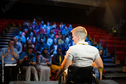 Speaker in wheelchair on stage cheering with audience