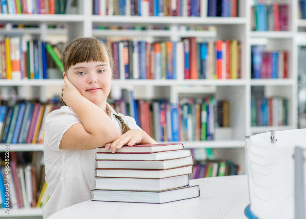 Young girl with syndrome down at library. Education for disabled children concept Young girl with syndrome down at library. Education for disabled children concept