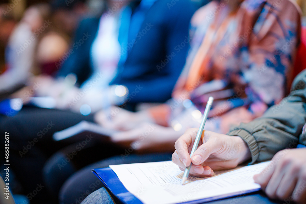 Business people taking notes in conference audience Business people taking notes in conference audience