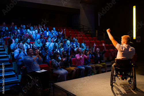 Speaker in wheelchair on stage cheering with audience
