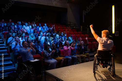 Speaker in wheelchair on stage cheering with audience