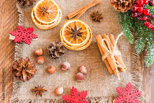 rustic Christmas composition - spruce branch with berries and cones, dried orange slices, nuts, onis on burlap. top view. photo