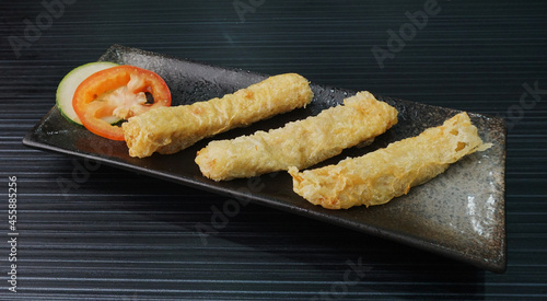 deep fried golden long fish paste wrapped in beancurd skin lobar wuxiang on dark grey wood background dim sum halal menu