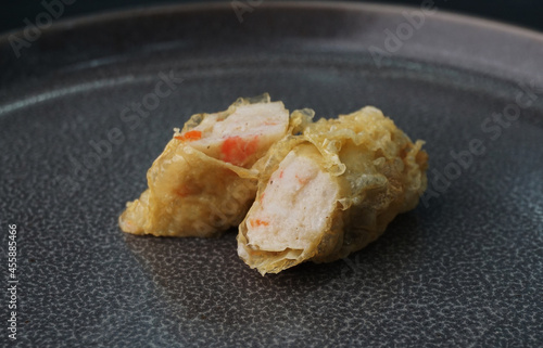 deep fried golden long fish paste wrapped in beancurd skin lobar wuxiang on dark grey wood background dim sum halal menu photo