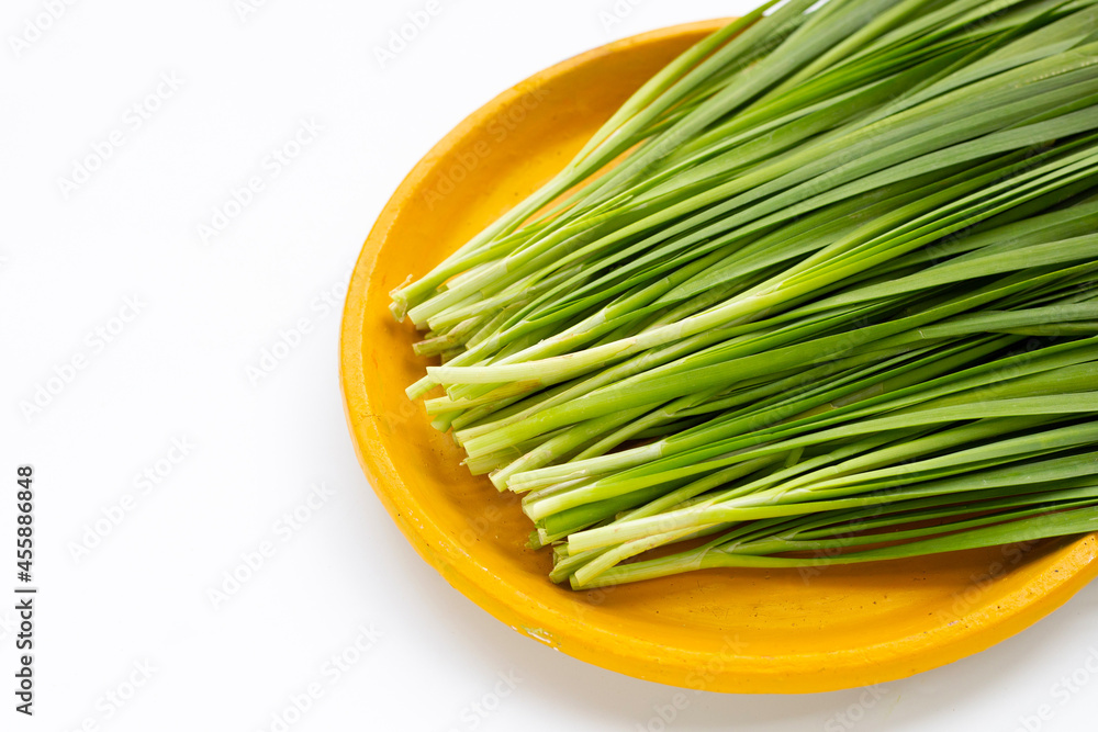 Fresh Chinese Chive leaves in yellow plate on white background. Fresh Chinese Chive leaves in yellow plate on white background.