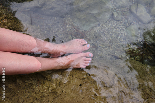 feet of an unrecognizable woman stuck in the cold water of a mountain river to improve the circulation of the blood. cardiovascular health, photo