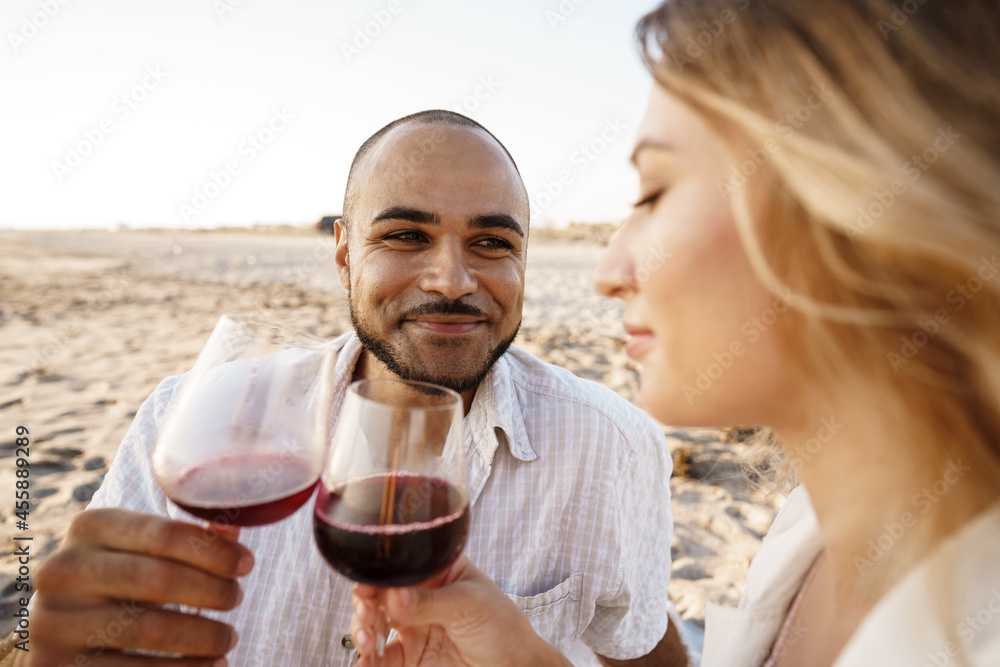Portrait of a young couple sitting on the beach and drinking wine Portrait of a young couple sitting on the beach and drinking wine