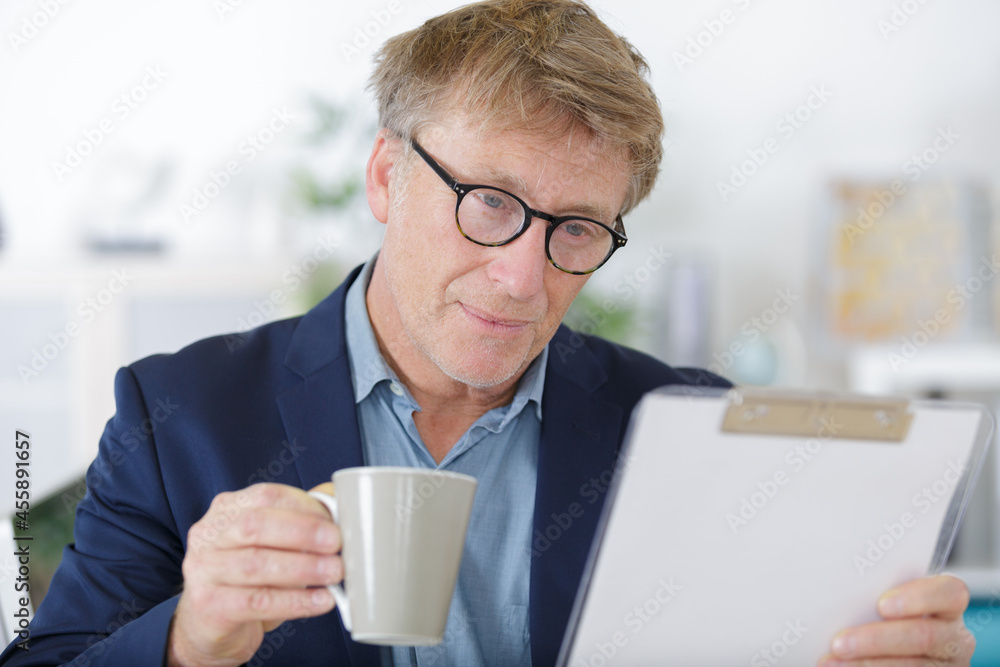 man reading clipboard with coffee mug on table man reading clipboard with coffee mug on table