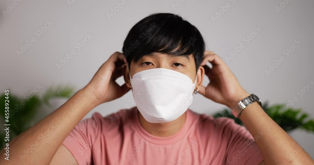 Man wearing face mask sits on couch in living room. Man wearing face mask sits on couch in living room.