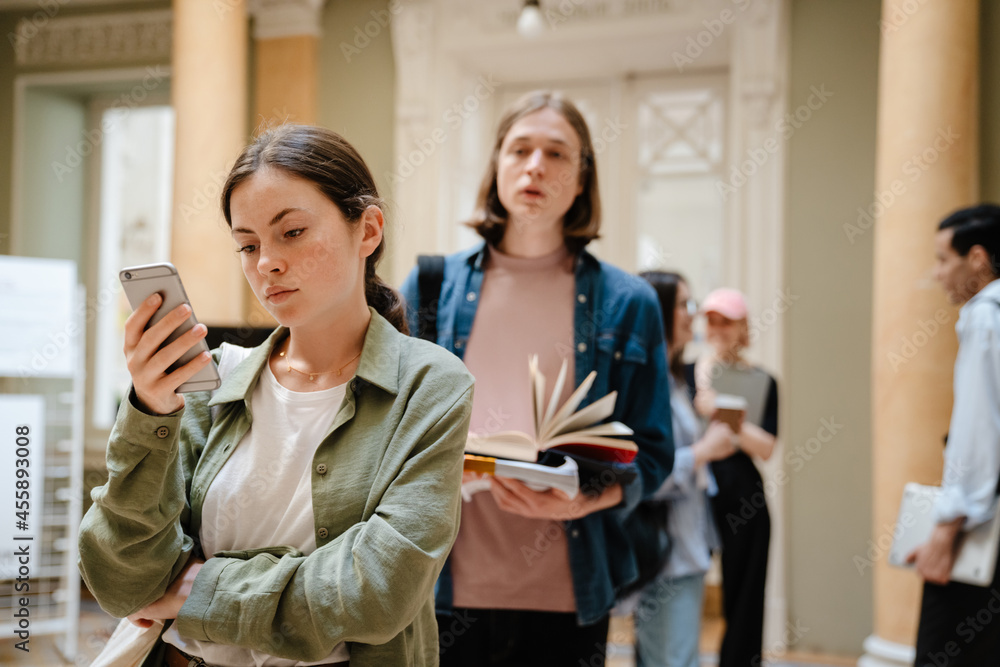 Young european students standing in line at library Young european students standing in line at library