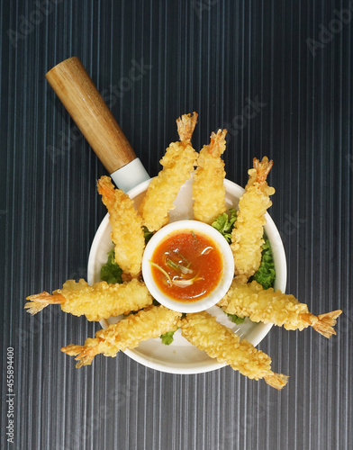 Japanese golden deep fried crispy tempura prawn with spicy chilli sauce in white bowl on dark grey wood background dim sum halal menu