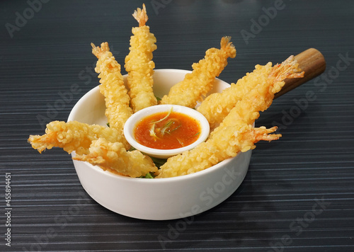 Japanese golden deep fried crispy tempura prawn with spicy chilli sauce in white bowl on dark grey wood background dim sum halal menu