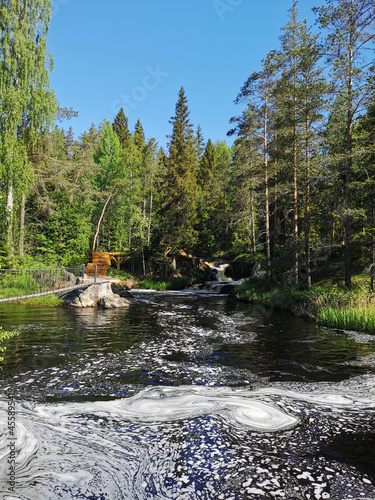 A picturesque waterfall on the Tokhmayoki River in Karelia surrounded by trees on a clear summer morning. photo