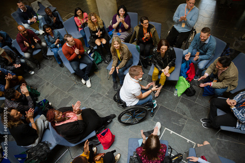Attentive audience listening to female speaker in wheelchair