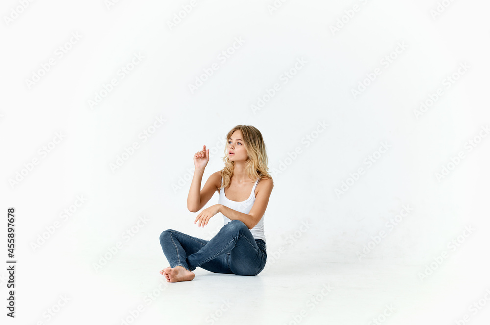 woman in jeans sitting on the floor fun emotions studio isolated background