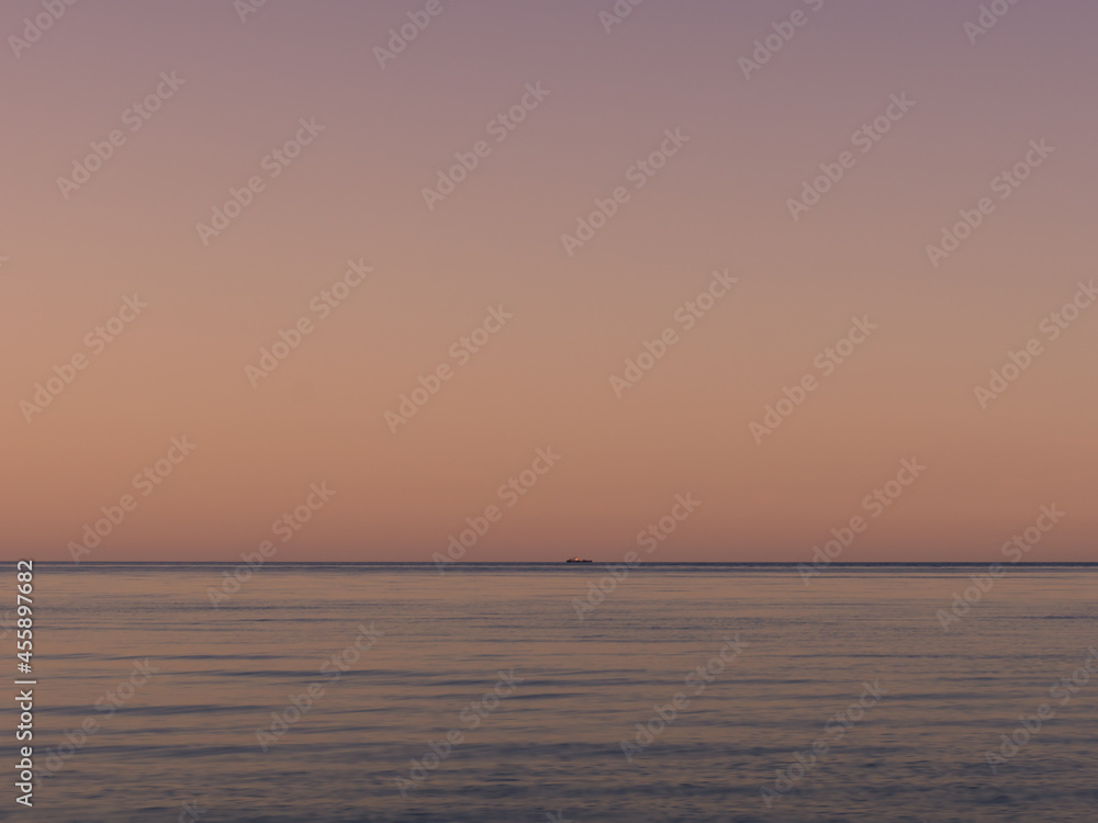 Fototapeta premium Small ship on the horizon in sunset.