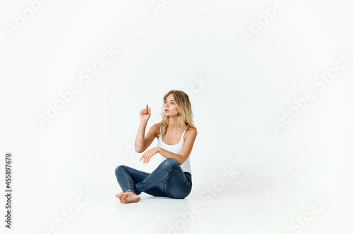 woman in jeans sitting on the floor fun emotions studio isolated background