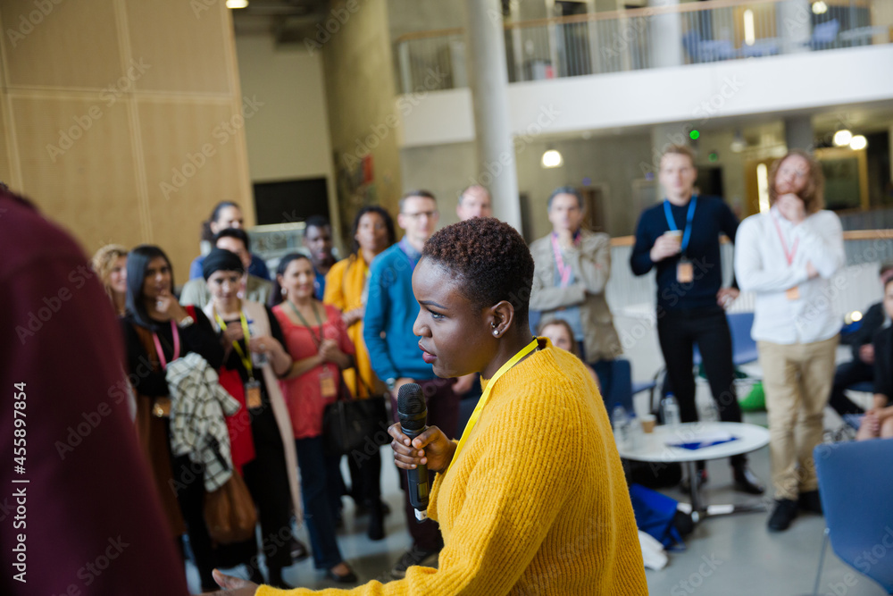 Female speaker with microphone talking to audience Female speaker with microphone talking to audience