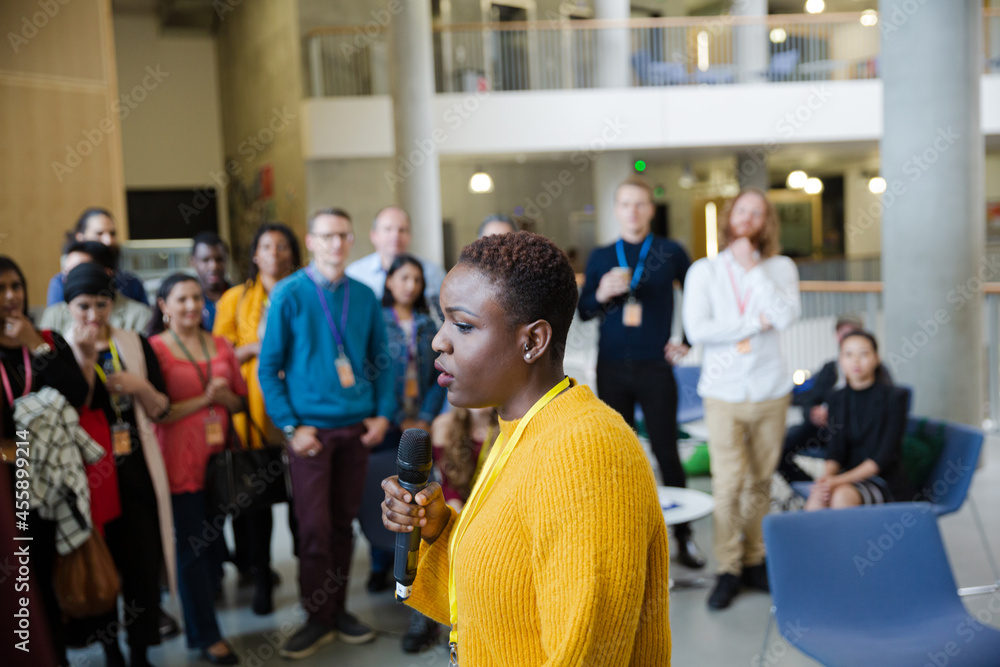 Female speaker with microphone talking to audience Female speaker with microphone talking to audience