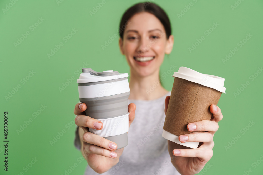 © Drobot Dean - Young brunette woman smiling while showing takeaway cups © Drobot Dean - Young brunette woman smiling while showing takeaway cups