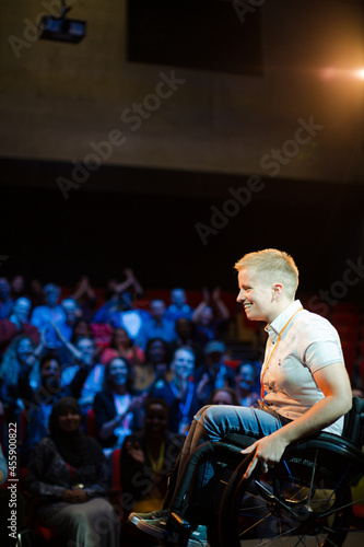 Female speaker in wheelchair on stage talking to audience